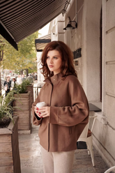 a lady in a brown unisex coat and a pair of beige pants